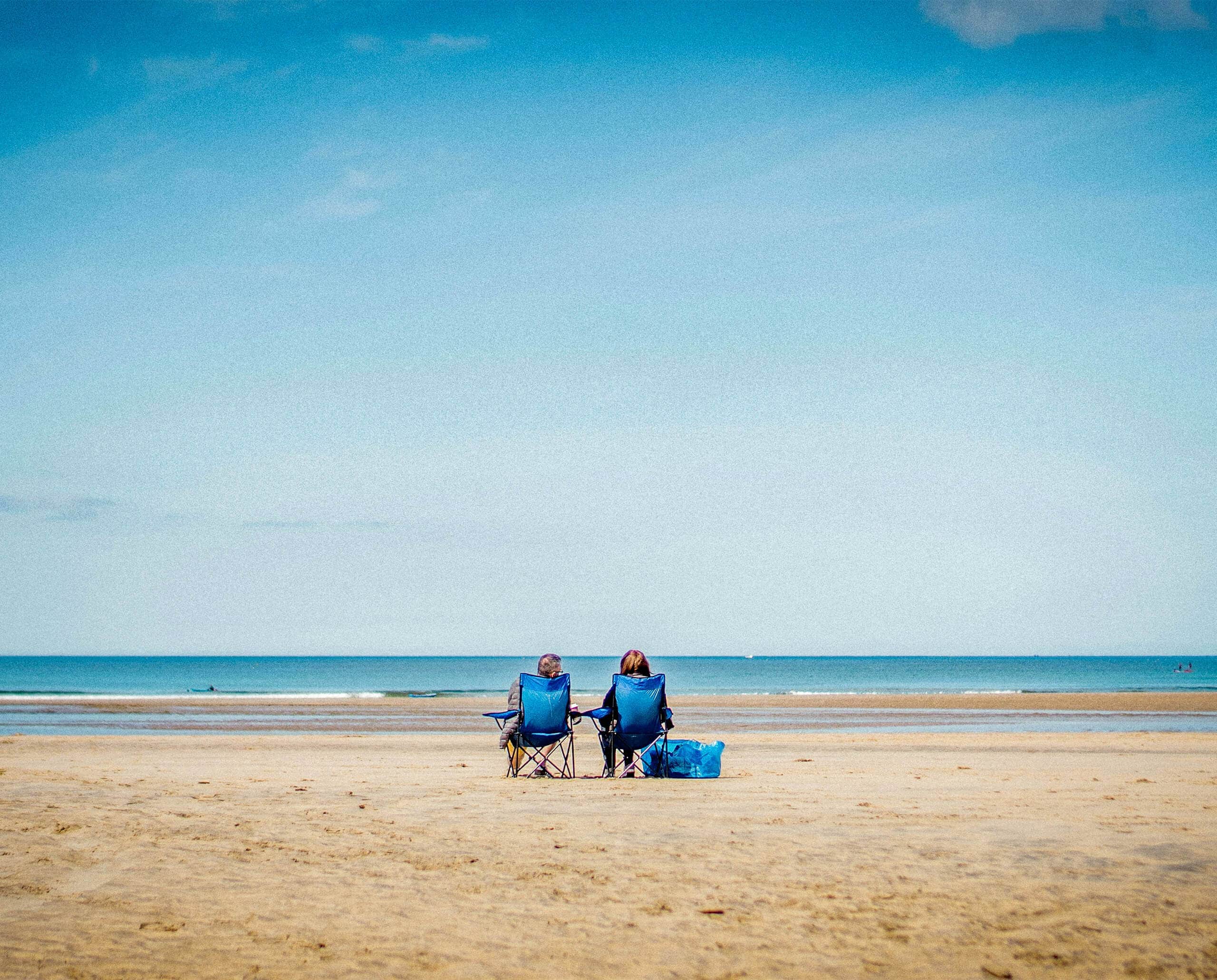 People resting on beach in blue folding chairs