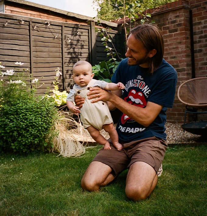 Men holding a baby in the garden